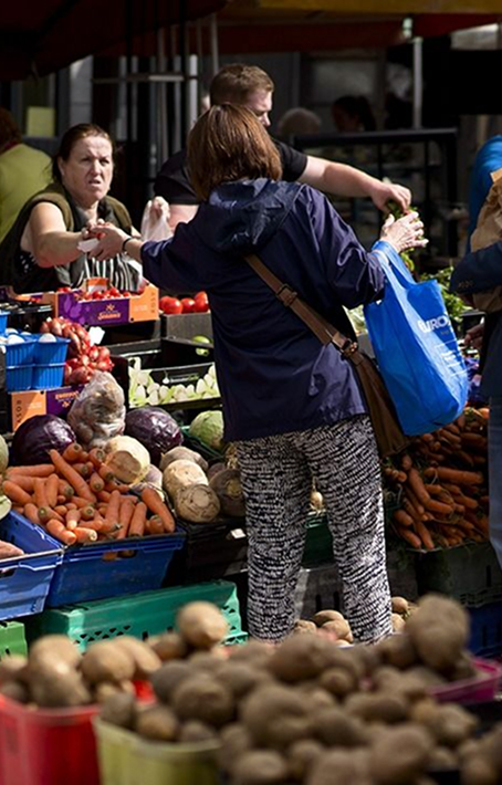 Person reaching for vegetables at a produce stall