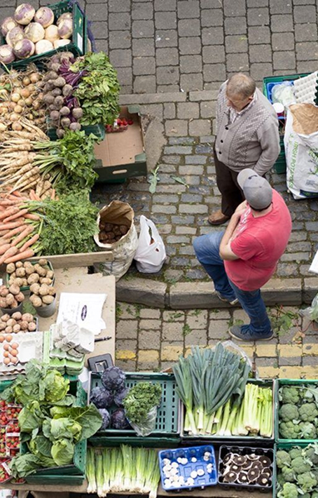 Shoppers examining root vegetables at a market