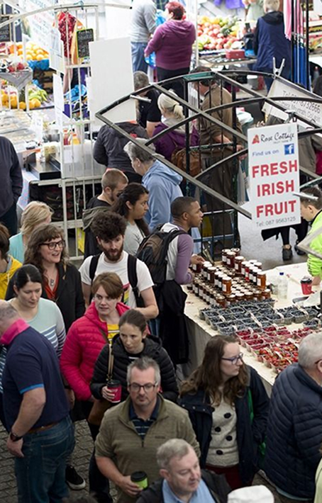 Crowded market scene with fresh fruit sign visible