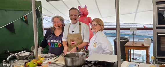 Group of chefs at a cooking demo inside a market tent